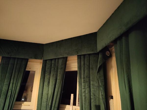 Picture of the installed pelmet, three green velvet panels running down from the ceiling to overlap the rail